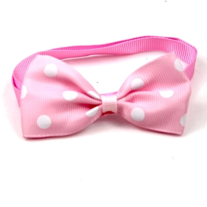 Close-up of pink polka dot pet bowtie accessory with ribbed fabric texture on white background