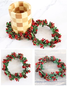 Detail of Christmas candle wreath with red green berries and natural pine cones