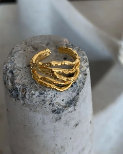 Macro shot of gold textured irregular lava ring on minimalist concrete pedestal