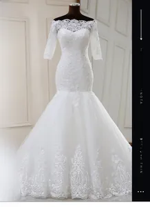 Détail d'une robe de mariée sirène à épaules dénudées avec dentelle florale et paillettes