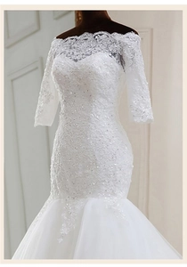 Détail du décolleté aux épaules dénudées avec dentelle de cils sur robe de mariée sirène