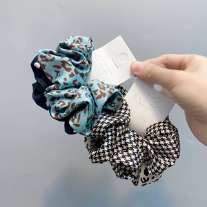 Detail view of stylish leopard and houndstooth satin scrunchies with brand tags