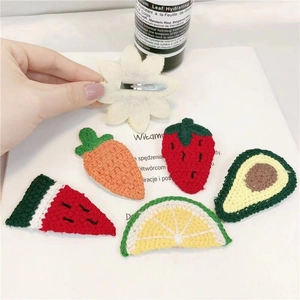 Macro detail of assorted handmade crochet hair clips featuring fruit and vegetable designs