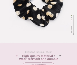 Close-up of black velvet scrunchie with beige polka dots showing soft fabric texture