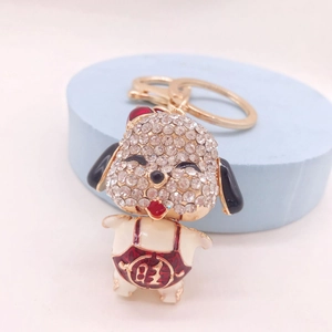Cartoon dog keychain with rhinestones and red enamel overalls on a blue pedestal