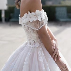 Elegant ivory off-shoulder wedding dress with 3D floral lace and beaded tassels