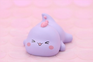 Close-up of cute purple and pink cartoon dinosaur figure for cake decoration