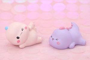 Close-up of cute pink and purple cartoon dinosaur resin figures for cake decoration