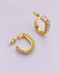 Detailed view of D-shaped gold earrings with rectangular zircon channel setting