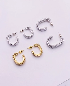 Macro shot of U-shaped gold and silver earrings featuring pave-set square cubic zirconia