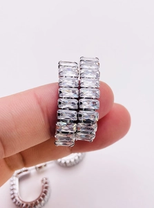 Macro detail of hand-held silver earrings with micro-paved square cubic zirconia stones