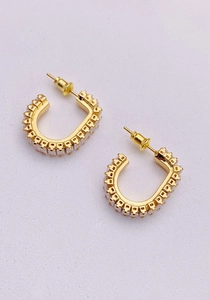 Macro detail of U-shaped gold earrings with micro-pave white cubic zirconia stones