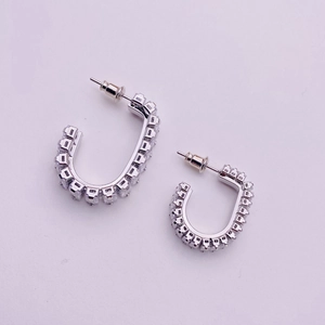 Macro shot of silver U-shaped earrings featuring micropave square cubic zirconia crystals