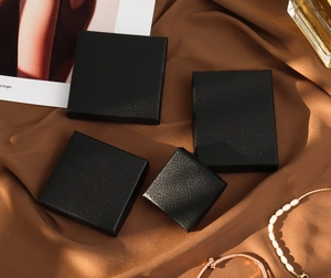 Various sizes of black jewelry boxes with lychee texture on luxury brown satin fabric
