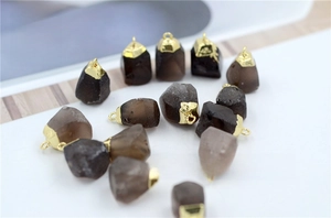 Detailed close-up of natural smoky quartz raw stone pendants with gold metal edging caps