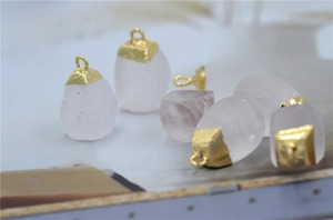 Macro shot of natural clear quartz crystal pendants with textured golden plated caps