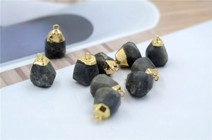 Macro detail of irregular raw faceted natural stone pendants with golden plated caps