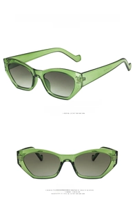 Detail view of transparent green irregular cat-eye sunglasses with gradient gray lenses