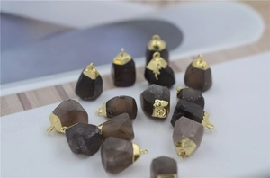 Detailed macro of natural raw smoky quartz pendants with gold plated caps and metal loops