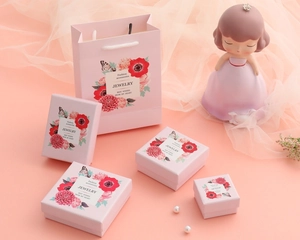 Close-up of pink floral jewelry boxes and matching gift bags with gold lettering