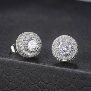 Macro shot of silver halo stud earrings with micro-pave cubic zirconia on a black surface