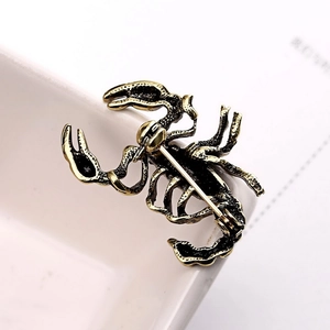 Macro detail of vintage scorpion brooch back featuring antique gold finish and safety pin