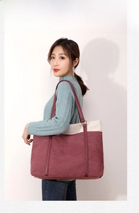 Detail of color-block canvas tote bag with burgundy straps and premium textured fabric