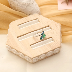 Detail view of peacock ring with green gemstone on a hexagonal wooden display stand