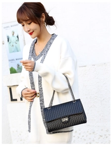 Close-up of black woven leather texture with silver metal chain strap and square buckle