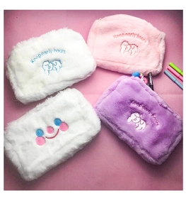 Detail of plush cosmetic bags with cute sheep embroidery and smiley face on pink background