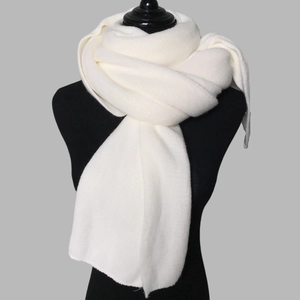 Close-up of white knitted winter scarf texture displayed on a black mannequin torso