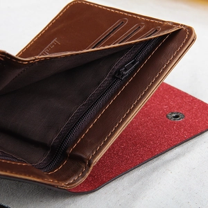 Detail of dark brown leather wallet showing coin zipper and red lining with card slots