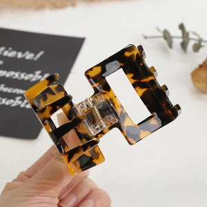 Elegant tortoise shell rectangular hair claw clip with golden spring held by hand