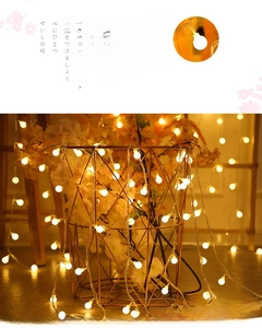 Detail of warm yellow LED bulb string lights inside a metal basket with pink flowers