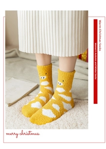 Close-up of thick coral fleece winter socks with yellow cow print and cute animal embroidery