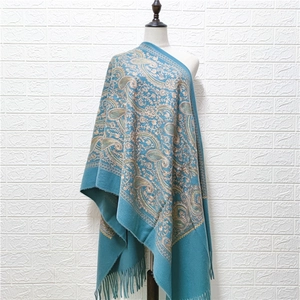 Blue cashmere-like shawl with paisley embroidery and tassels on a mannequin display