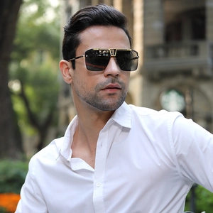 Close-up of oversized square sunglasses with black-grey gradient lenses and gold frame