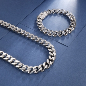 Detail of silver Cuban link chain set with rhinestone-encrusted buckle on blue background