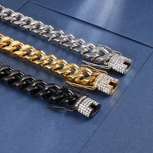 Detail of Cuban chain bracelets in gold, silver and black with rhinestone buckle accents