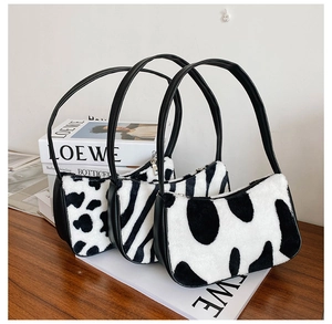 Detailed close-up of plush zebra and cow print underarm bags on a wooden surface