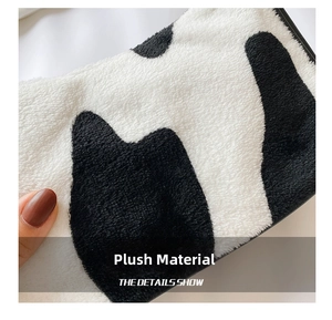 Close-up of the soft plush material and black and white cow print texture on the handbag