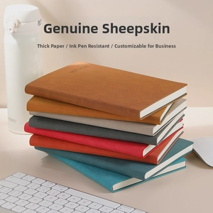 Stack of multi-colored A5 faux leather notebooks with embossed text on office desk