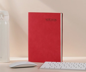 Macro shot of a red leather business notebook with a textured cover on a clean desk