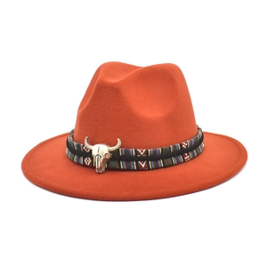 Detail of bright orange fedora with ethnic woven band and silver bull skull ornament