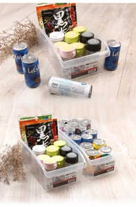 Clear plastic kitchen storage bin organizing soda cans and snacks on a wooden table