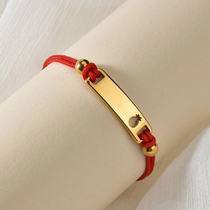 Detail of red woven cord bracelet with a curved 18K gold plate and polished beads
