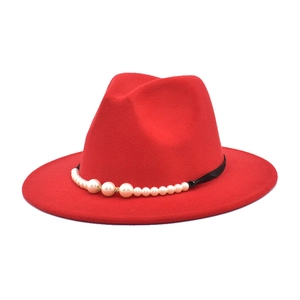 Detail of red wool fedora with elegant black ribbon and gradient white pearl accents