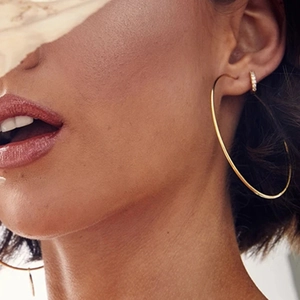 Minimalist large gold hoop earrings and sparkling crystal stud worn by model