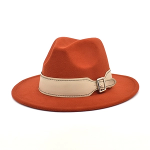 Detail of orange wide brim fedora hat featuring beige leather band and silver buckle