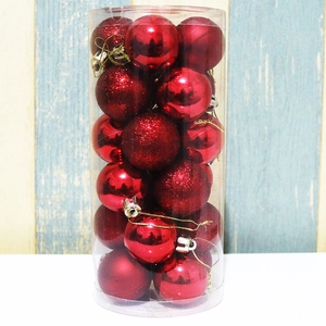Detail of red Christmas ornaments in glossy, matte, and glitter finishes in a clear tube